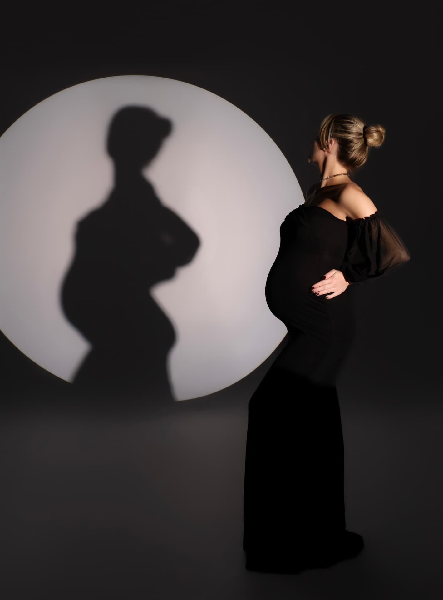 Zwangere vrouw in het donker, met haar schaduw in een lichtcirkel