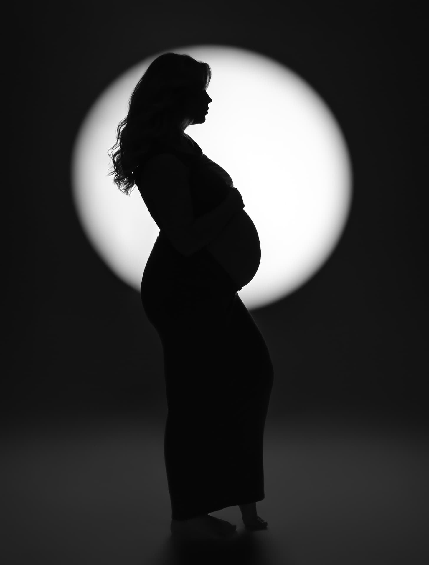 Silhouet van een zwangere vrouw in een lichtcirkel, in zwart-wit