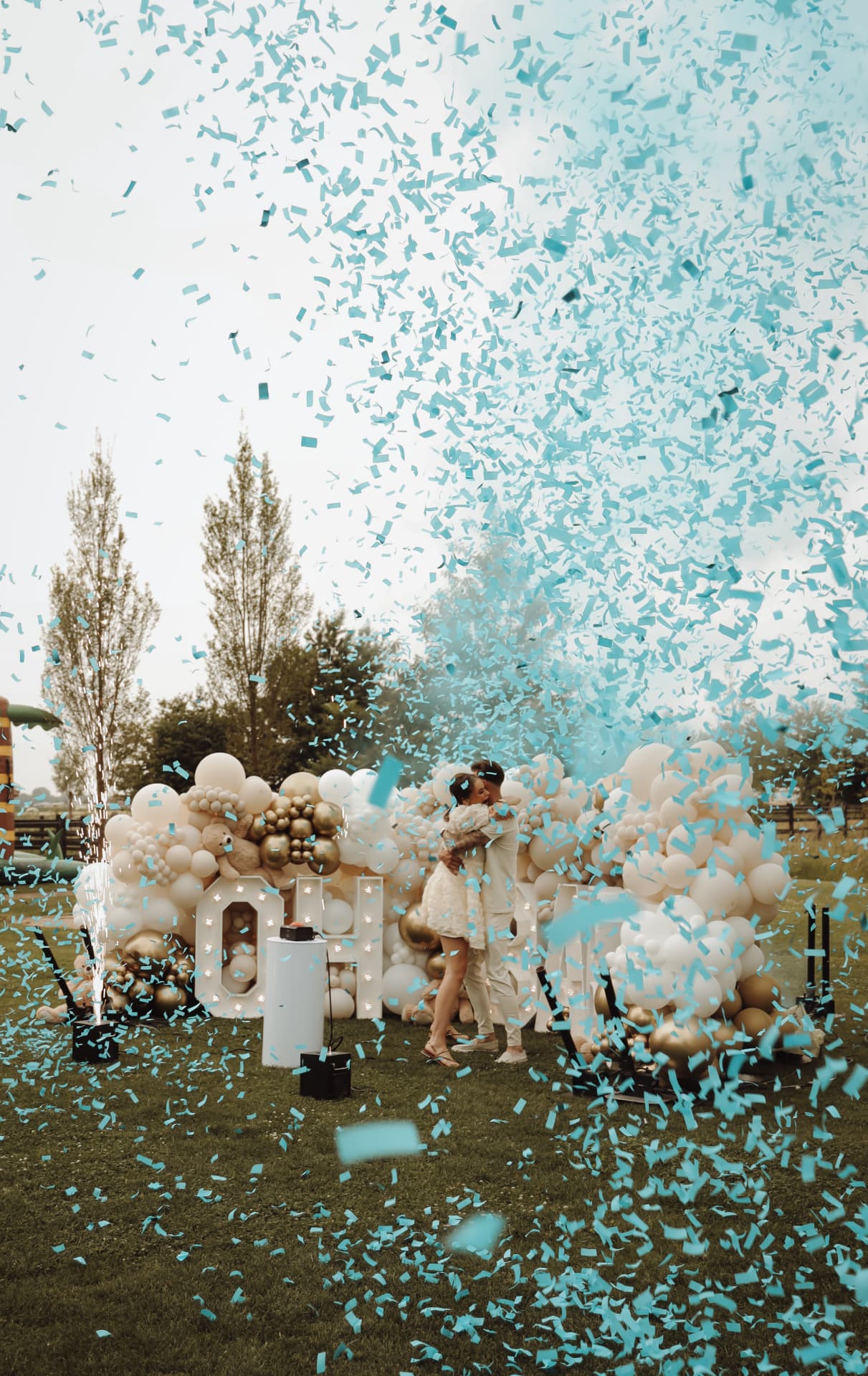 Stel kust tijdens een gender-reveal met blauwe confetti en ballonnen